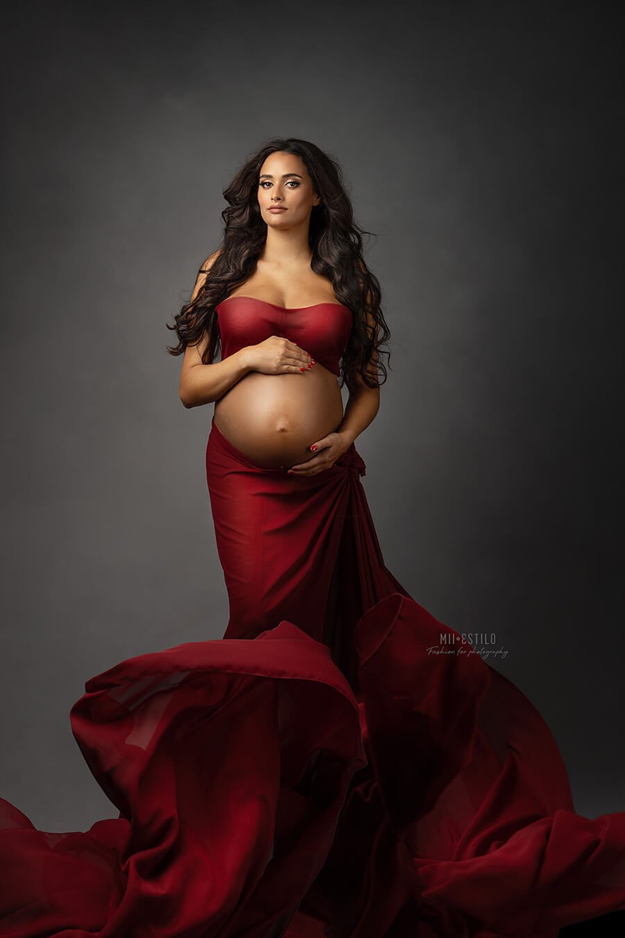 brunette pregnant model with long hair poses wearing a bordeaux chiffon scarf tied on her waist as a skirt and covering her breast as a top. 