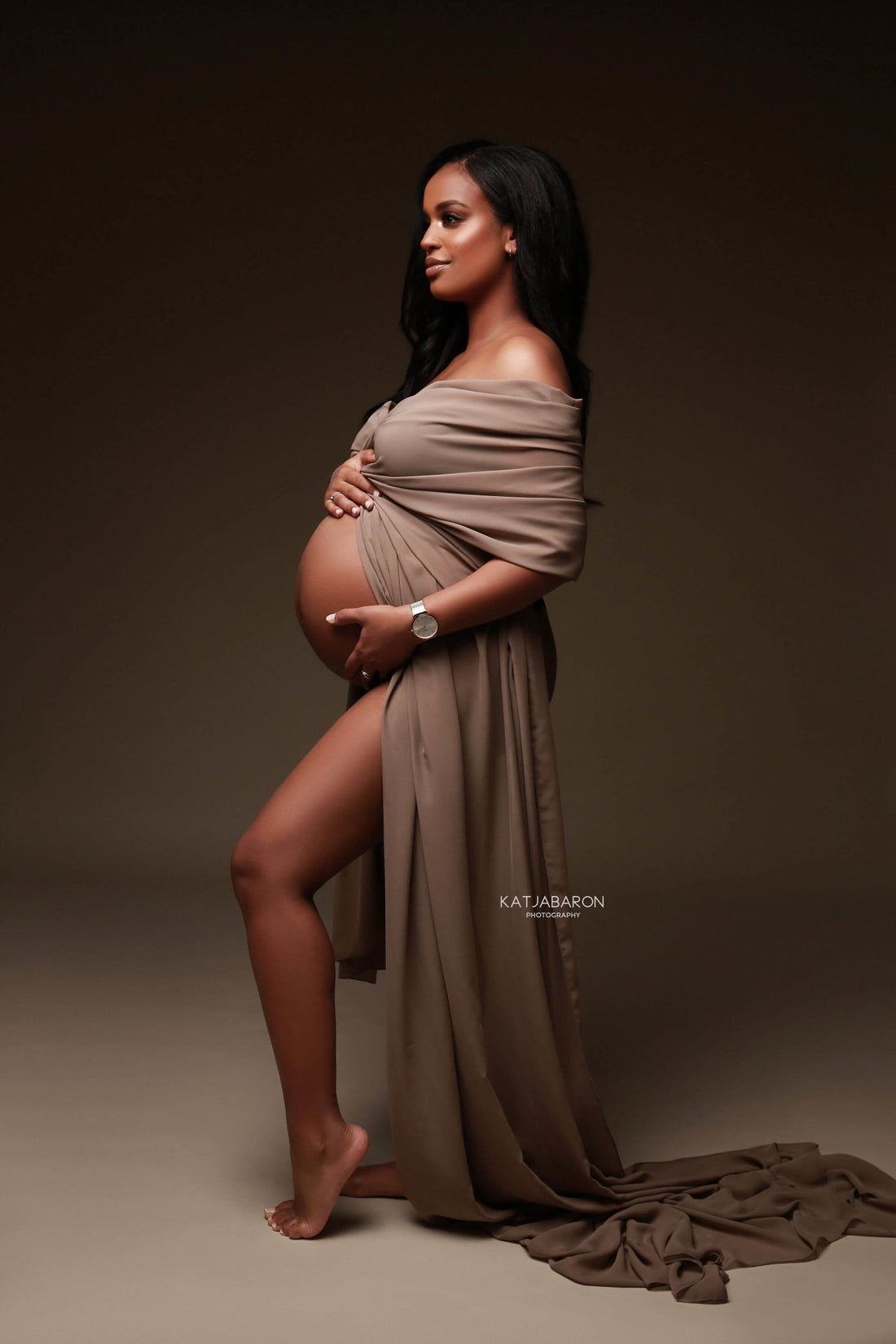 model with dark hair poses in a studio with a espresso chiffon scarf wrapped around her arms.