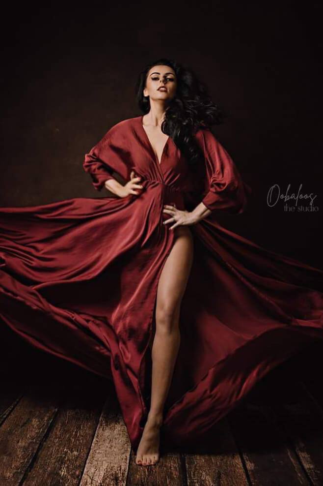 This model is posing in a long dress. The dress is being blowed to the back for a gorgeous effect. The color is cherry and the material is silky