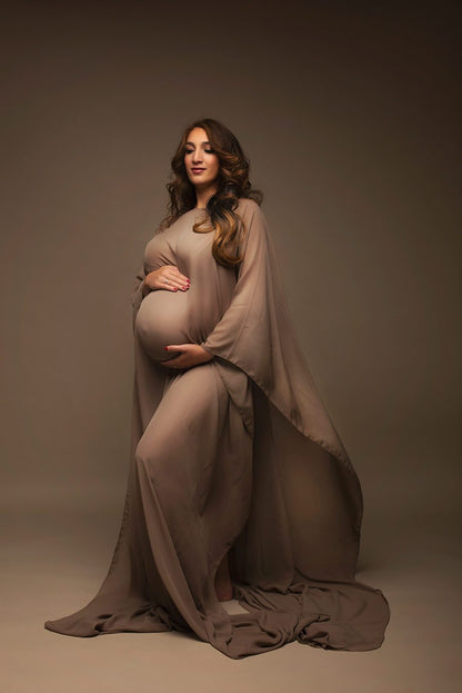 Brown haired pregnant model poses with an espresso chiffon cape. The cape covers her whole body and she looks to the side while posing. 